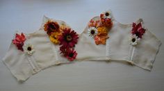 three white bras with flowers on them sitting on top of a wooden table next to a cup