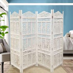 a room divider made out of white wood with intricate carvings on the top and sides