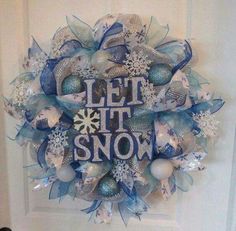 a wreath that says let it snow on the front door with blue and silver decorations