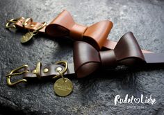 two brown leather bow ties on a rock with a gold keychain attached to it