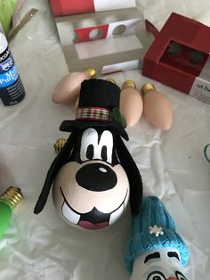 mickey mouse and goofy the dog ornaments on a table with other disney character figurines