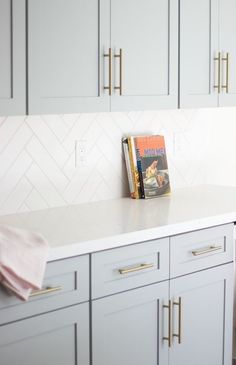 a kitchen with white cabinets and gold handles