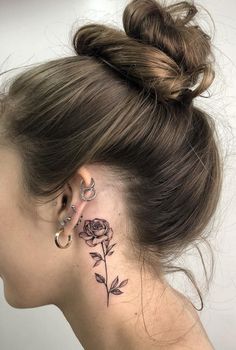 a woman's neck with a rose tattoo on her left side behind the ear