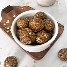 a white bowl filled with oatmeal energy bites on top of a wooden cutting board