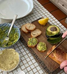 a person cutting bread with avocado and other toppings on a wooden board