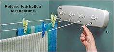 a hand is pulling clothes from a line on a towel rack and hanging it with clips