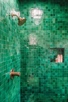 a bathroom with green tiles and a shower head