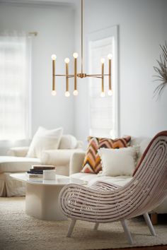 a living room with white couches, chairs and a chandelier hanging from the ceiling