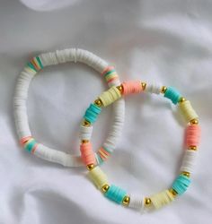 two bracelets with different colored beads on white fabric