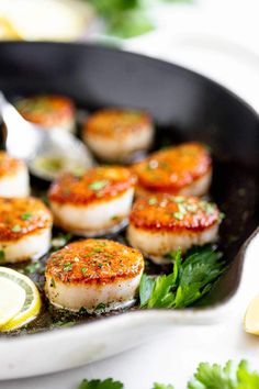 seared scallops in a cast iron skillet with lemon wedges and parsley