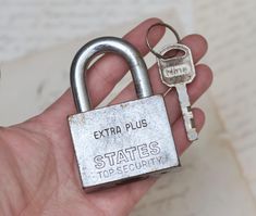 a hand holding a metal padlock with the word extra plus written on it and two keys attached to it