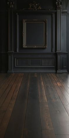 an empty room with black walls and wooden floors