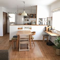 an open kitchen and dining room with wood flooring, white walls and wooden furniture