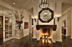 a living room filled with furniture and a fire place under a large mirror on the wall