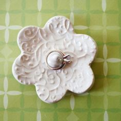 a white flower shaped object with a ring on it's center and a green checkered tablecloth