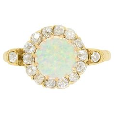 An enchanting opal takes centre stage in this stunning Victorian cluster. The 0.50 carat opal is sit within 18 carat yellow gold claws and is surrounded by a halo of fourteen old cut diamonds, with an additional stone set on each shoulder. The diamonds total 0.48 carat, they match in colour at G whilst ranging in clarity from VS to SI. The ring itself has been exquisitely hand crafted in 18 carat yellow gold with intricate carvings featuring down each shoulder. Gemstone: Opal Stone Shape: Caboch Victorian Engagement Rings, Victorian Rings, Centre Stage, Halo Diamond Ring, Opal Stone, Diamond Solitaire Engagement Ring, Diamond Cluster Ring, Three Stone Rings, Diamond Cluster