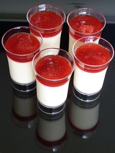 four glasses filled with liquid sitting on top of a black table next to each other