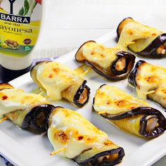 stuffed eggplant and cheese rolls on a white plate next to a bottle of ketchup