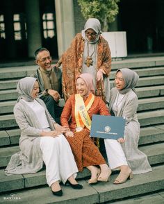 a group of women sitting on top of steps in front of a building with one woman holding a plaque