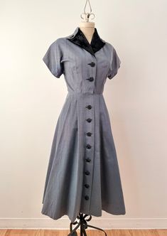 Gorgeous '40s/50s cusp 'New Look' style shirtwaist dress with short dolman sleeves, padded shoulders, nipped waist and a pleated front with full button closure .  This babe is impeccably made with attention to detail.  The collar is made of black silk velvet and  features decorative, rhinestone encrusted buttons at each tab.  The fabric has a nice weight to it with black and grey/blue stripes and black buttons down the full length of the front.  There are also pockets hidden in the pleats of the Retro Semi-formal Dresses With Buttons, 1950s Style Vintage Short Sleeve Dress For Work, Vintage Dress With Covered Buttons And Short Sleeves, Vintage Semi-formal Dresses With Buttons, Classic Short Sleeve Vintage Dress For Vintage Events, Classic Vintage Dress With Short Sleeves For Vintage Events, Classic Short Sleeve Vintage Dress, Formal Vintage Dress With Short Sleeves And Buttons, 1950s Vintage Dress With Buttons For Formal Occasions