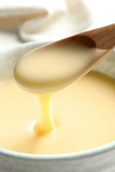 a spoon is pouring liquid into a bowl