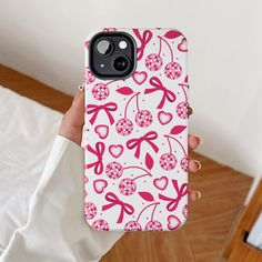 a person holding up a phone case with hearts and bows on it in front of a bed