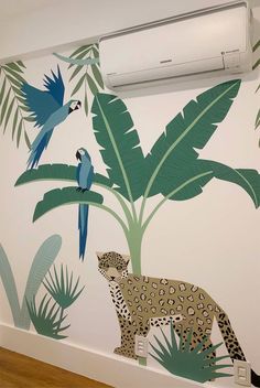 an air conditioner mounted to the side of a wall next to a leopard and bird mural