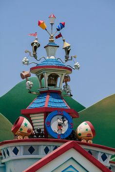 a clock on top of a building with mickey mouse figurines and other decorations