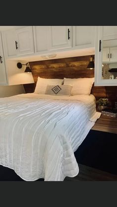 a white bed sitting in a bedroom next to a wooden headboard and night stand