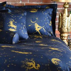 a bed with blue and gold sheets on top of it next to a brick wall