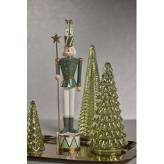 a nutcracker figurine standing next to three christmas trees on a tray