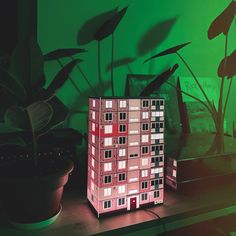 a house model sitting on top of a wooden table next to a potted plant