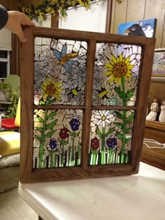 a stained glass window sitting on top of a counter next to a vase filled with flowers