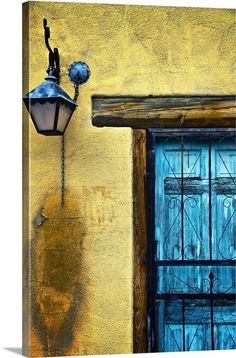 an old fashioned street light on the side of a building with a blue door and window