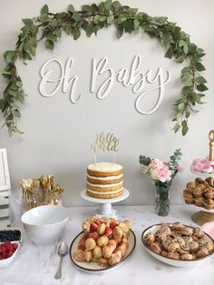 a table topped with cakes and desserts next to a sign that says oh baby