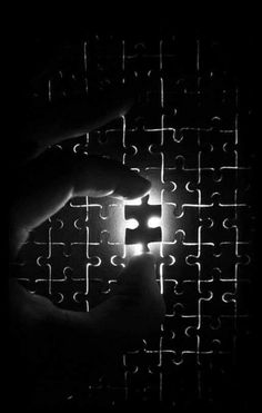 a person's hand is holding a piece of jigsaw puzzle in the dark