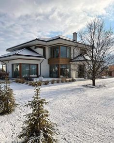 a large house is covered in snow and has two trees on the side of it