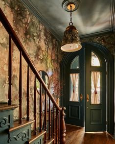 an entryway with green doors and wooden stairs, painted in shades of teal