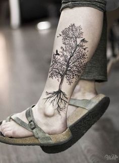 a person with a tree tattoo on their foot and the bottom part of her leg