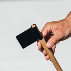 a hand holding a wooden stick with a black lighter in it