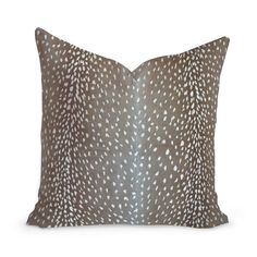 a brown and white pillow with an animal print on the front, sitting on a white background