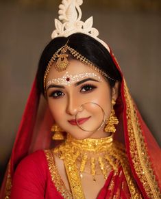 a woman wearing a red and gold bridal outfit with an elaborate head piece on her head