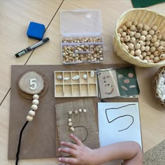 a child's hand is on the table next to some beads and other items