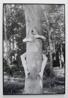 a black and white photo of a person hugging a tree