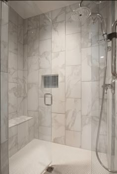 a walk in shower sitting next to a white tiled wall and floor with a glass door