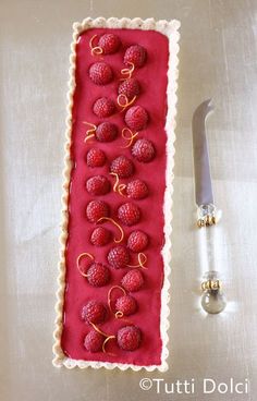 a cake with raspberries on it next to a knife