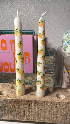 two white candles sitting on top of a wooden block