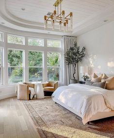 a large bed sitting in the middle of a bedroom under a chandelier above a window