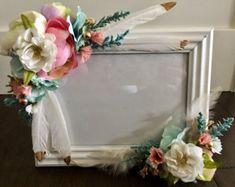 an old photo frame decorated with flowers and feathers