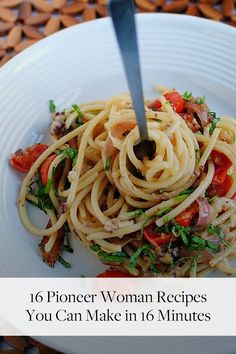 a white plate topped with pasta and vegetables on top of a wooden table next to a fork